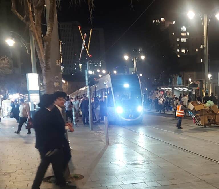 הרכבת הקלה בירושלים נוסעת בלילה ברחוב יפו, עם קהל נוסעים והולכי רגל
