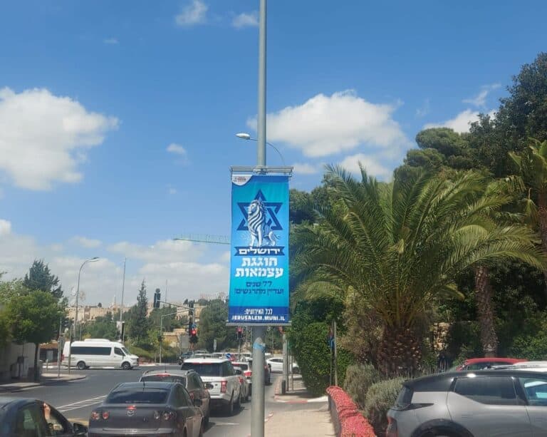 כרזת חגיגות יום העצמאות בירושלים, על רקע שמיים כחולים ועצי דקל