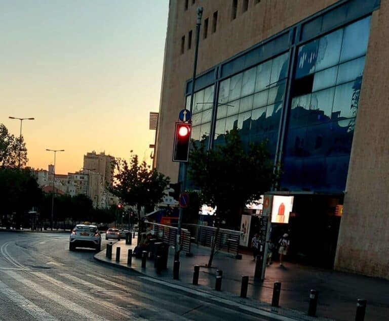 צילום של התחנה המרכזית בירושלים עם רמזור אדום ברקע, בשעת ערב, מבט מהרחוב לעבר הבניין