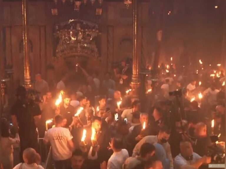 טקס האש הקדושה בכנסיית הקבר בירושלים, עשרות מאמינים אוחזים בלפידים בוערים באווירה חגיגית וסמלית