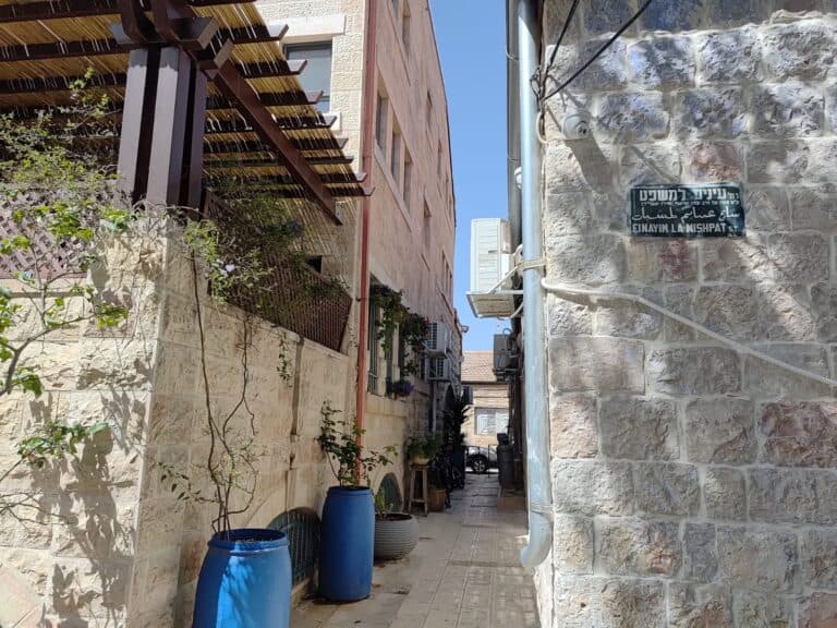 שלט רחוב 'עיניים למשפט' על קיר אבן ישן בירושלים