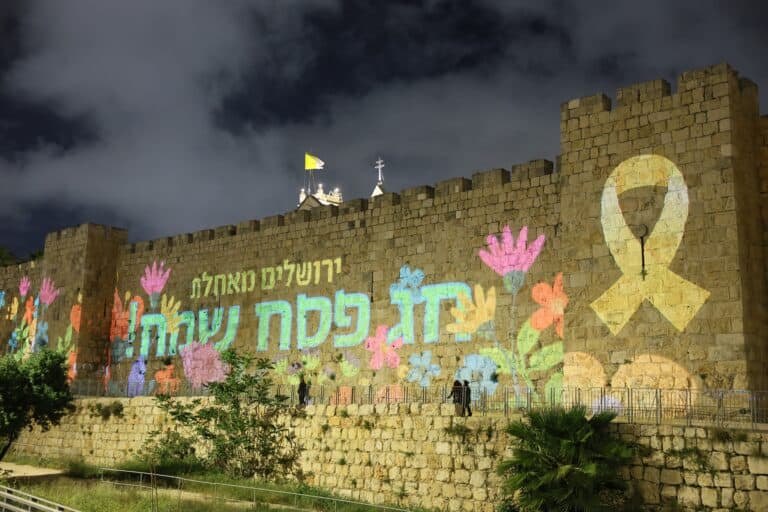 הארה חגיגית על חומות העיר העתיקה בירושלים עם כיתוב "חג פסח שמח", לקראת חג הפסח 2025
