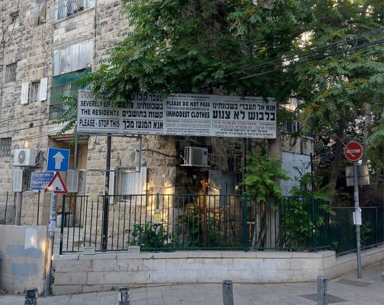 A sign in Jerusalem's Geula neighborhood asking passersby to wear modest clothing, photographed May 2025