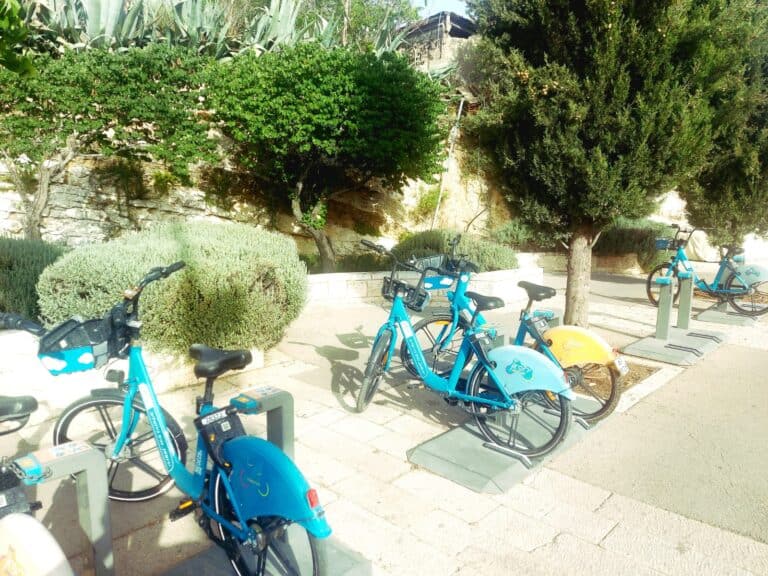 תחנת אופניים שיתופיים ברחוב דוד רמז בירושלים – ריקה מרוכבים, עם אופניים בצבעי כחול וצהוב
