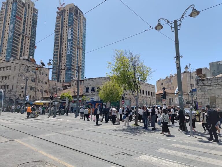 הולכי רגל במסלול הרכבת קלה ברחוב יפו בירושלים, ברקע עבודות תשתית ומגדלים