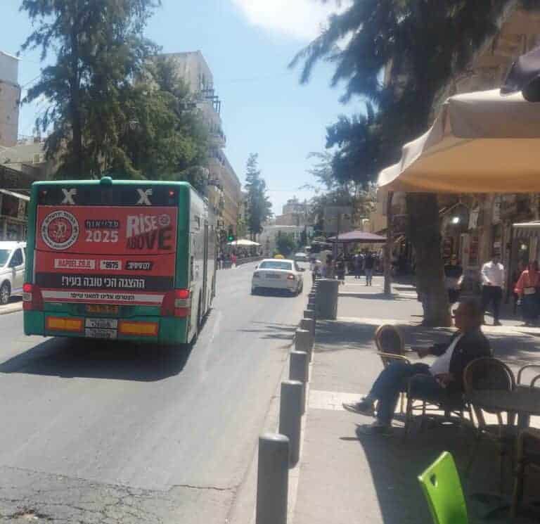 שמש חזקה בצהריים בירושלים, אוטובוס חולף ליד בתי קפה מוצלים ברחוב קינג ג'ורג'