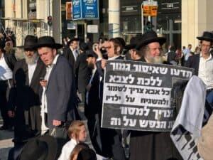 מפגינים חרדים בהפגנה נגד גיוס ברחוב שרי ישראל ירושלים עם כרזה.