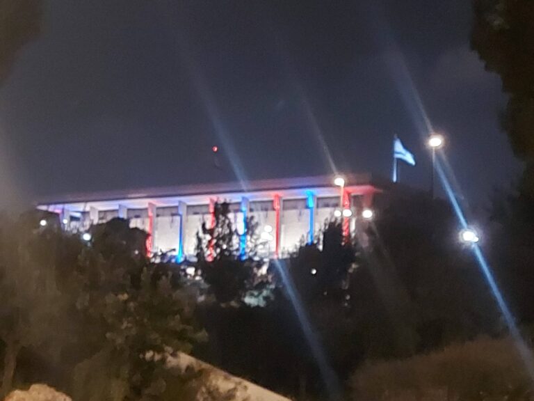 The Knesset building in Jerusalem lit up with blue, white and red lights at night