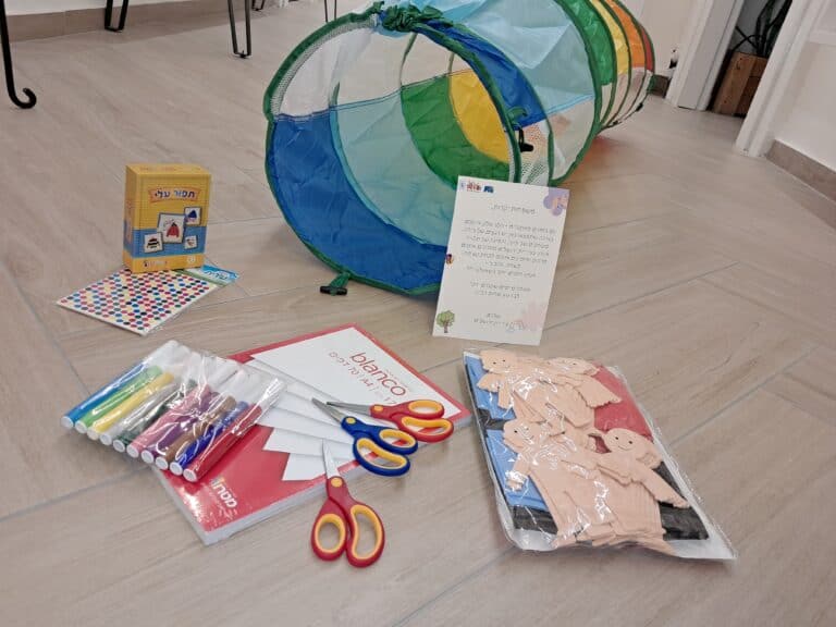 Children’s activity kit distributed in public shelters in Jerusalem, including markers, scissors, stickers, and a colorful play tunnel