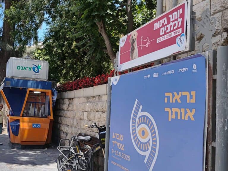 Municipal signs in Jerusalem: a dog park campaign above a local identity poster, next to a street lottery booth