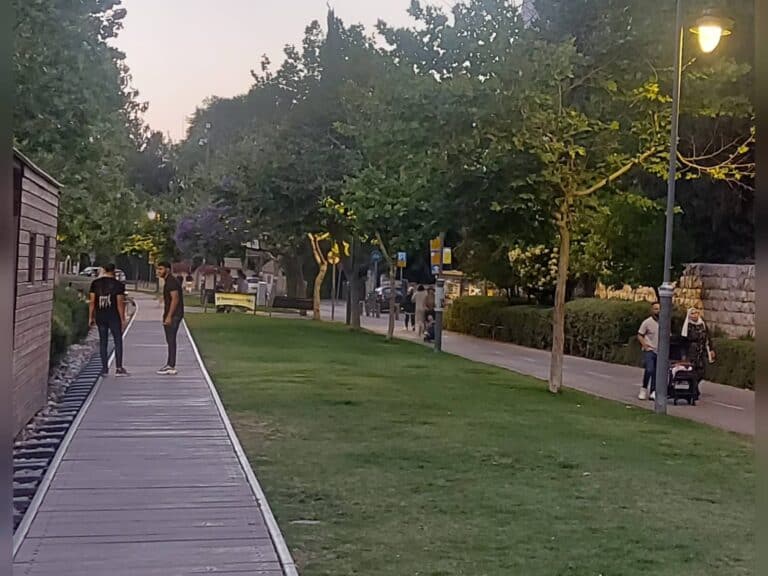 People walking quietly in Jerusalem's Mesila Park at dusk