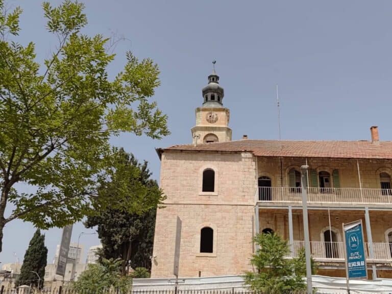 A historic stone building with clocktower in central Jerusalem under clear skies