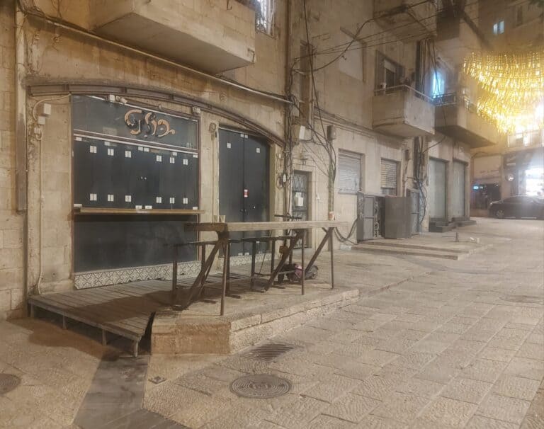The closed front of Bulint bar in Jerusalem, with a faded sign and an empty table — a silent reminder of the city’s vanished media scene and bohemian nightlife