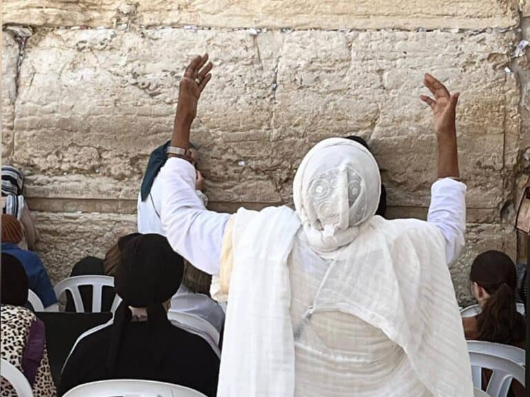 A woman raises her hands in prayer at the Western Wall in Jerusalem before Tisha B’Av