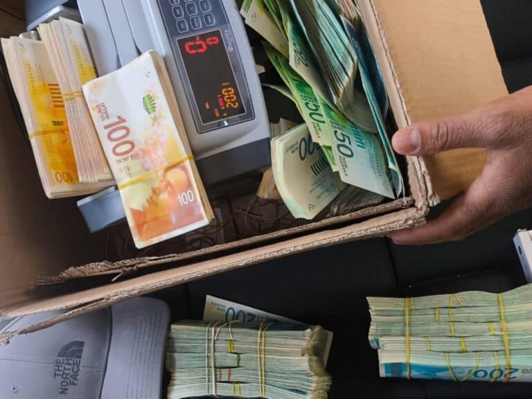 Stacks of Israeli cash and weapons seized during a fraud investigation in Jerusalem ar