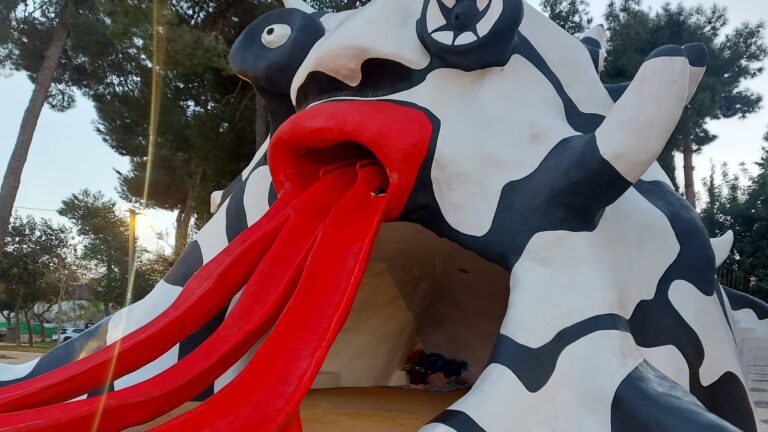 אדם וכלבו תחת פסל המפלצת בגן רבינוביץ' שבשכונת קריית יובל בירושלים (Photo: Jerusalem Online News - Yuli Kraus)