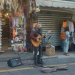 מוזיקאי רחוב מנגן בגיטרה בשוק מחנה יהודה בירושלים בזמן מבצע שאגת הארי