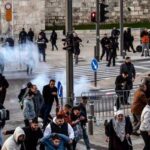 עימותים בין מתפללים פלסטינים לכוחות משטרה סמוך לשערי העיר העתיקה בירושלים במהלך עיד אל-פיטר, גז מדמיע נראה באוויר