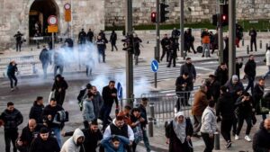 Fidèles palestiniens affrontent la police près des portes de la vieille ville de Jérusalem pendant l’Aïd al-Fitr avec du gaz lacrymogène visible