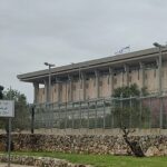 בניין הכנסת בירושלים לצד שלט קריית בן גוריון ודגלי ישראל