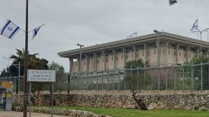 בניין הכנסת בירושלים לצד שלט קריית בן גוריון ודגלי ישראל