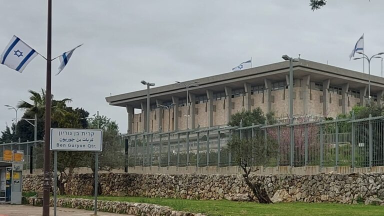 בניין הכנסת בירושלים לצד שלט קריית בן גוריון ודגלי ישראל