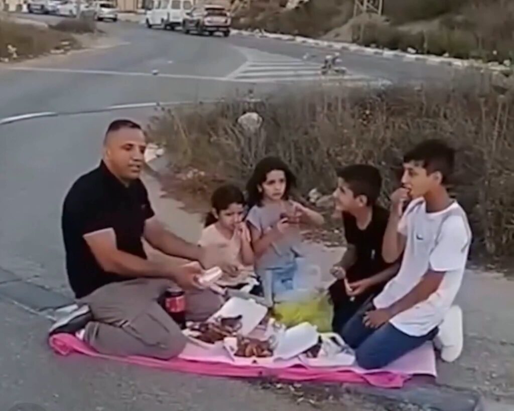 אב מבית איכסא סועד עם ילדיו סמוך למחסום הצבאי לאחר שנאסרה כניסתו לכפר