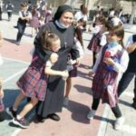 נזירה מוקפת תלמידות ותלמידים בחצר בית ספר נוצרי במזרח ירושלים