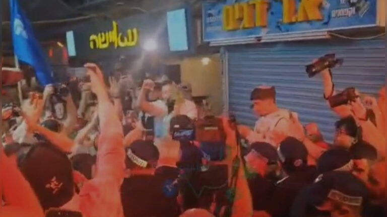 תומכי בנימין נתניהו מניפים ידיים וטלפונים במהלך ביקורו בשוק מחנה יהודה בירושלים לקראת הבחירות לכנסת